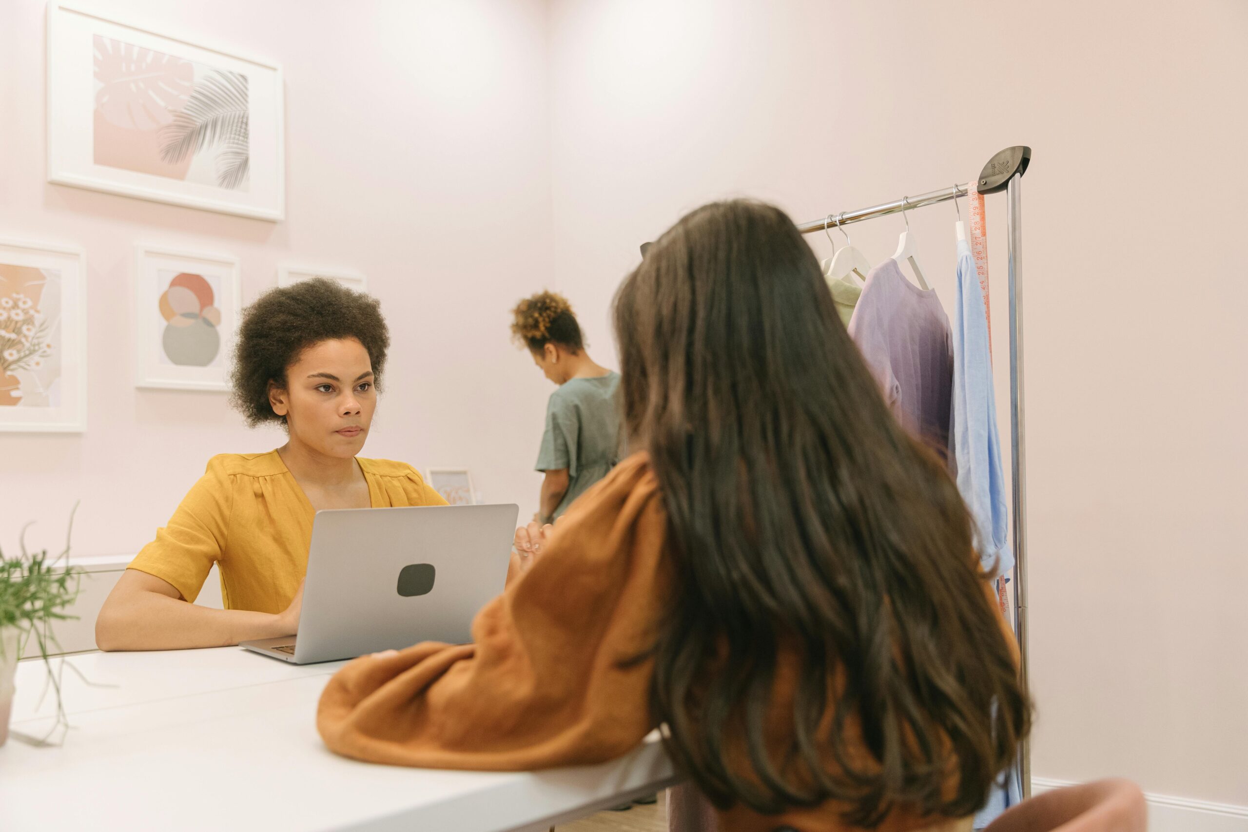 Two women in a stylish office setting working on a laptop and discussing projects.